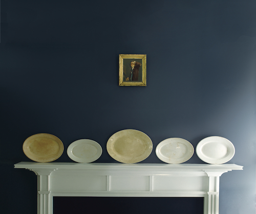 A Benjamin Moore Hale Navy HC-154 wall with a white mantelpiece and gold decor accents