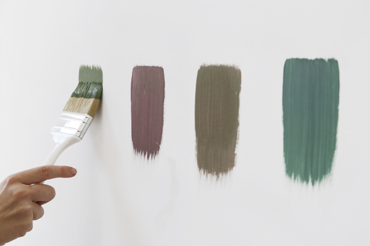 Person painting paint swatches directly on the wall