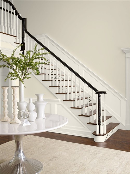 Open interior hall and staircase with walls in Benjamin Moore Navajo White OC-95, contrasting with trim in Benjamin Moore Balboa Mist