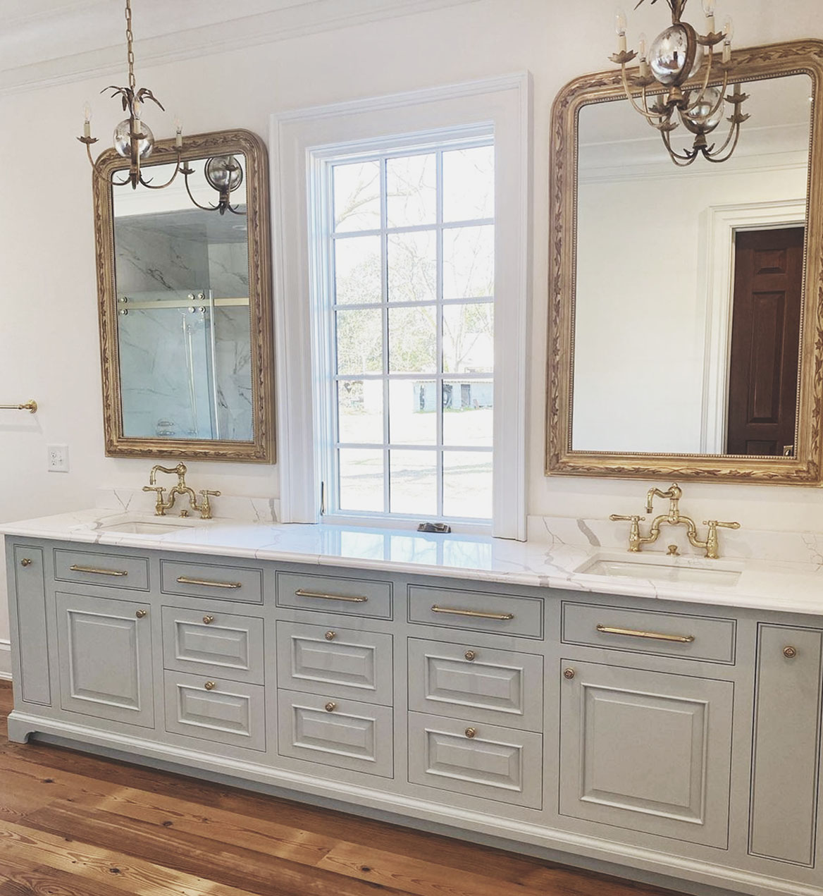 Bathroom double vanity with brass faucets, drawer pulls, and cabinet knobs