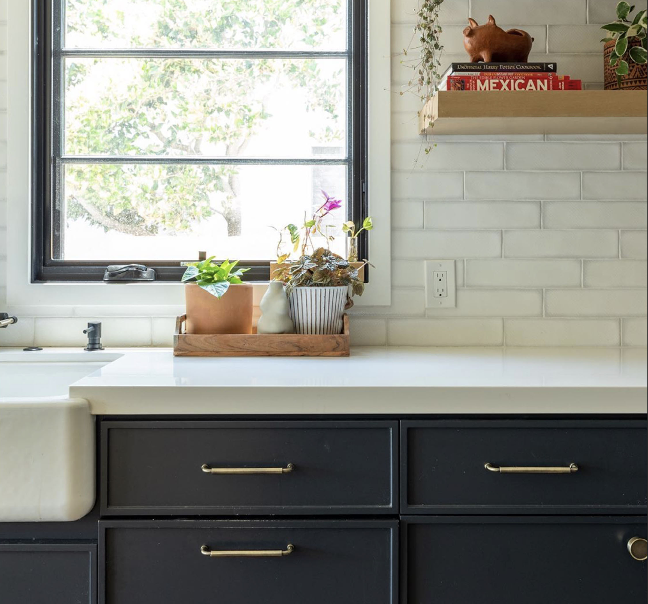 Kitchen with dark cabinets, white tile backsplash, and brass hardware 