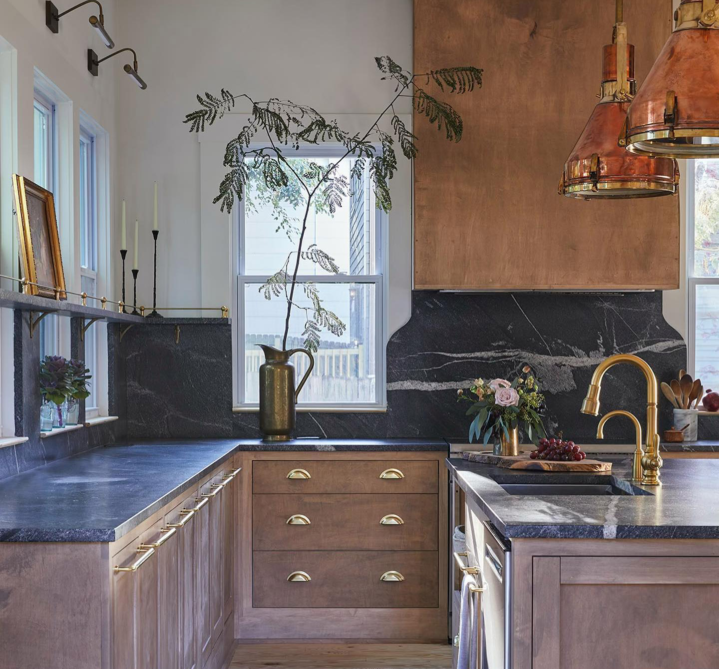 Kitchen with wood cabinets, black countertops, and Baldwin brass bar pulls and cup pulls