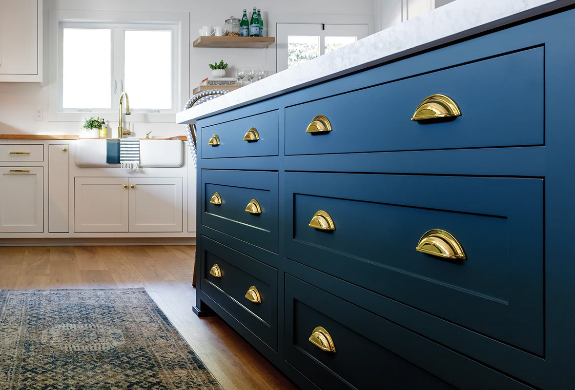 Kitchen with white cabinets and a blue island with brass knobs and pulls